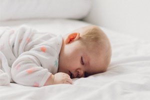 Ein süßes Baby der auf einem Bett, mit Metallfreie Lattenroste, schläft.